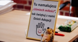 Ramka z plakatem zachęcającym do przyłączenia się do akcji malowania uśmiechniętej buźki, symbolu Światowego Dnia Adopcji