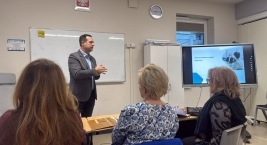 Mężczyzna prowadzi prezentację przed grupą słuchaczy w sali konferencyjnej