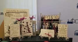 Stół z drewnianymi przedmiotami ozdobionymi świątecznymi dekoracjami wykonanymi przez przedsiębiorstwo społeczne. 