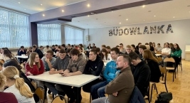 Uczestnicy zajęć siedzą przy stołach w klasie, angażując się w dyskusje