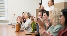 grupa osób siedzi przy stole i klaszcze