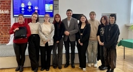 Grupa osób pozujących do zdjęcia przed ekranem
