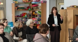 Kobieta stoi przed zebranym tłumem, dzieląc się swoimi myślami.