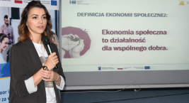 Prelegentka podczas prezentacji; na ekranie widoczny slajd z definicją ekonomii społecznej