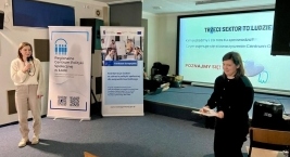 Dwie prelegentki podczas wystąpienia na sali konferencyjnej; w tle prezentacja z hasłem „Trzeci sektor to ludzie”